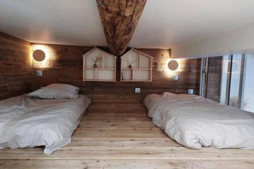 two beds in a room with wooden walls and wood floors at Idéalement situé cœur du village - calme & confort in Saint-Étienne-de-Tinée