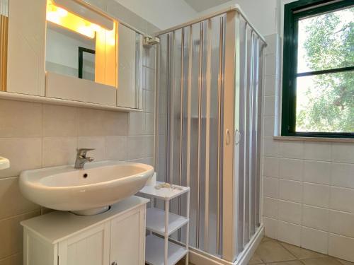 baño blanco con lavabo y ventana en Villetta San Matteo, en Mattinata