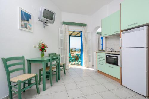 una cucina con tavolo, sedie e frigorifero di Victoria Studios & Apartments a Mikri Vigla