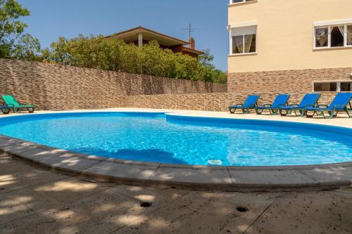 a swimming pool with blue chairs and a building at Lisbon Surf Hostel in Carcavelos