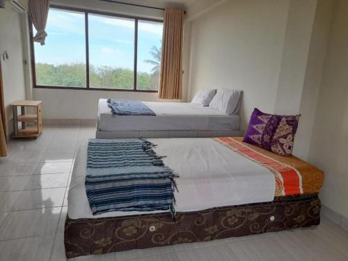 2 camas en una habitación con ventana grande en Kutabay Homestay, en Kuta Lombok