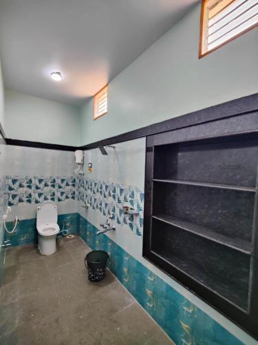 a bathroom with a toilet and a window in it at Srinivasa Homestay in Hampi