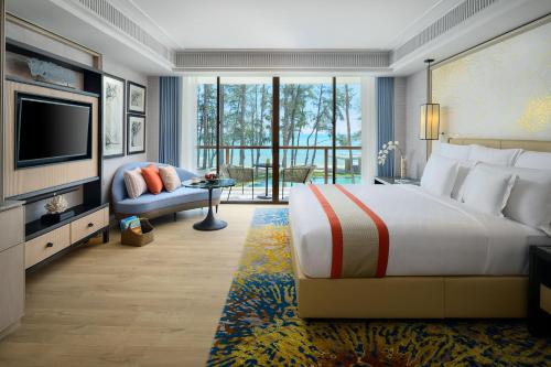 a bedroom with a bed and a tv and a couch at InterContinental Phuket Resort by IHG in Kamala Beach