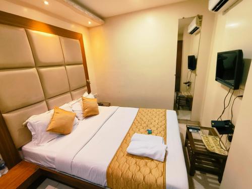 a bedroom with a bed with two pillows and a television at Apex Hotel in Mumbai