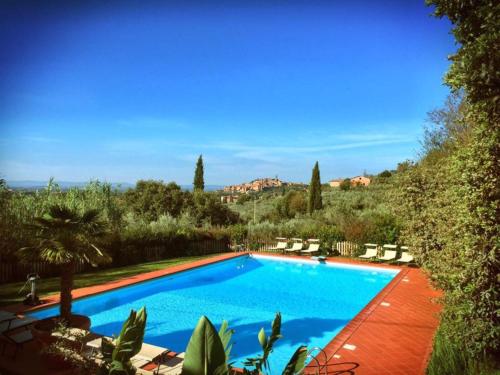 a swimming pool in a yard with chairs and trees at Borgo Dolci Colline Resort Ziraia in Castiglion Fiorentino