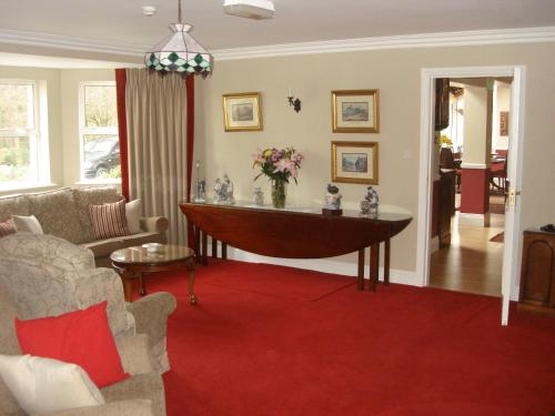 a living room with a table and a red carpet at Gleann Fia Country House in Killarney