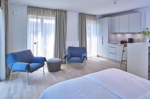 a bedroom with two chairs and a bed and a kitchen at Lüttjeod Apartmentvilla Lüttjeod Apartmentvilla 10 in Langeoog