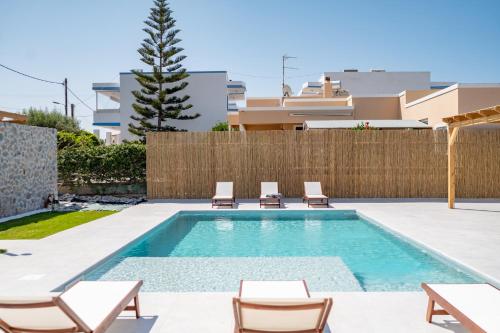 una piscina en un patio trasero con sillas y una valla en Villa Eos Mastichari - with heated pool en Mastichari