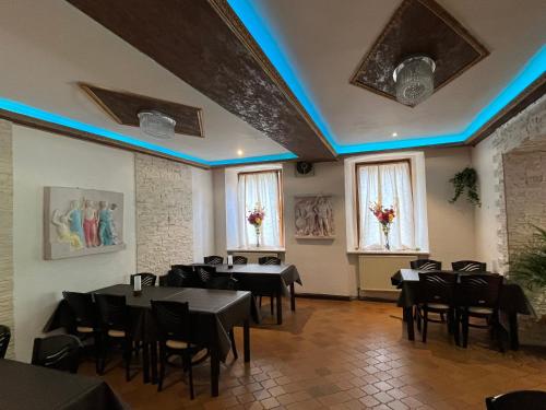 ein Restaurant mit Tischen und Stühlen in einem Zimmer mit blauen Lichtern in der Unterkunft Jamas Hotel & Restaurant in Pottenstein