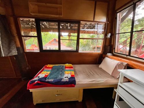 a small bed in a small room with windows at Good Life Dacha Wellness Homestay in Pai