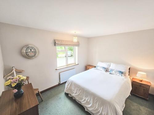 a bedroom with a white bed and a window at Lark Rise Holiday Home Glenbeigh in Glenbeigh