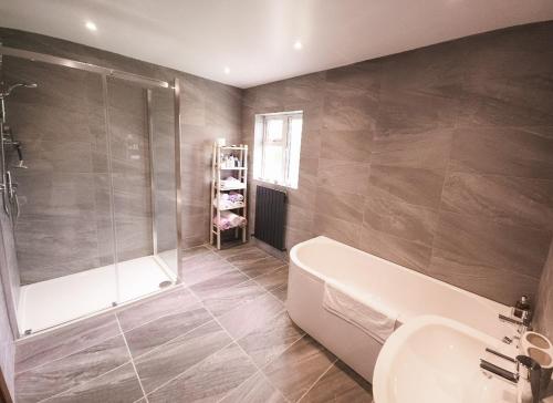 a bathroom with a shower and a tub and a sink at Lark Rise Holiday Home Glenbeigh in Glenbeigh