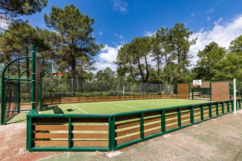 a tennis court with a green tennis court at Marina de Talaris, Lacanau, villa in Lacanau