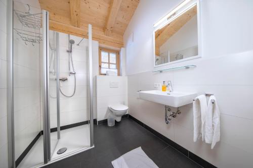 een witte badkamer met een wastafel en een douche bij Penthauswohnung am Sonnenhang in Neukirchen am Großvenediger