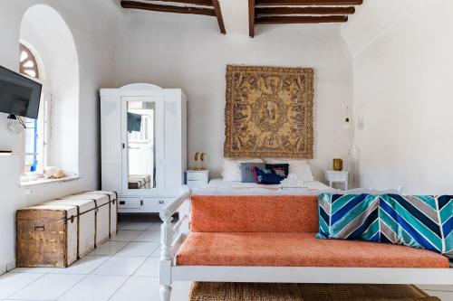 a bedroom with a bed and a couch and a mirror at Platia Tinos Cycladic Cottage in Platiá