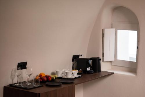 a counter with fruit and wine glasses on it at Twenty One Suites in Oia