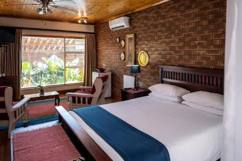 ein Schlafzimmer mit einem Bett und einer Ziegelwand in der Unterkunft Asante Guest House in Vanderbijlpark