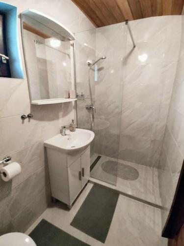 a white bathroom with a shower and a sink at Holiday home The Hive in Slunj