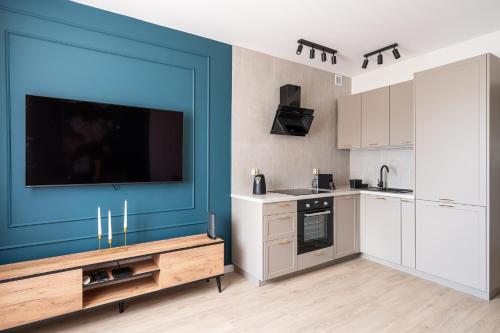 a kitchen with a flat screen tv on a blue wall at RentPlanet - Apartament Piłsudskiego in Wrocław