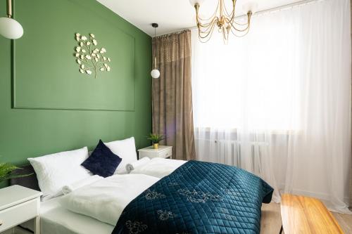 a green bedroom with a bed and a chandelier at RentPlanet - Apartament Piłsudskiego in Wrocław