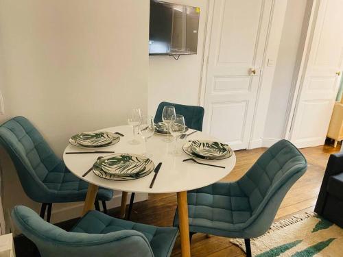 - une table blanche avec des chaises, des assiettes et des verres à vin dans l'établissement Mgic Apartment 4p Montmartre, à Paris
