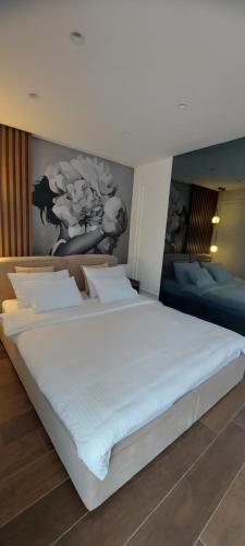 a bedroom with a large white bed with a painting on the wall at La casa di Sonja in Tivat
