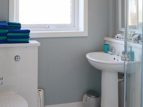 a white bathroom with a sink and a window at Cross Tides in Hilton of Cadboll