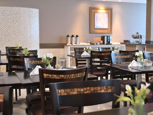 a dining room with tables and chairs and a bar at Hotel Araraquara By Mercure in Araraquara