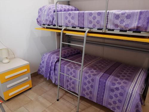 a bedroom with three bunk beds with purple sheets at Casa vacanze Gemini in Triscina
