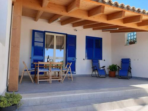 a patio with blue shutters and a table and chairs at Casa vacanze Gemini in Triscina