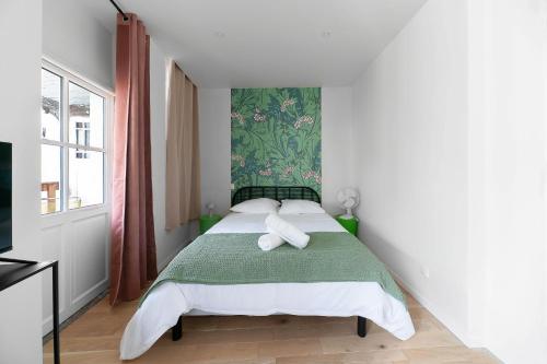 a bedroom with a bed with a green and white blanket at Résidence Aristide Briand - Appartements en Centre Ville in Vichy