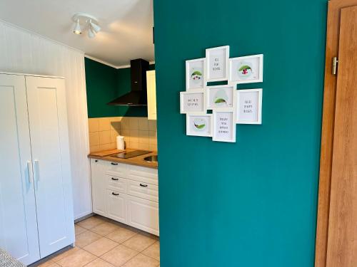a kitchen with a blue wall with pictures on the wall at Studio Apartma Olive, Nova Gorica, Slovenia in Nova Gorica