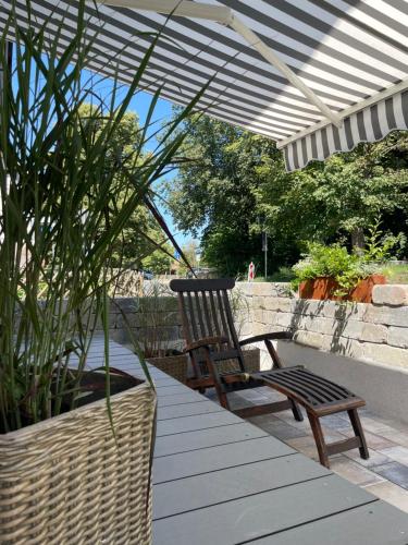 un patio con una silla y un banco bajo una sombrilla en Villa Pauline - FeWo Bordeaux en Bad Sooden-Allendorf