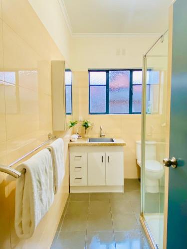 a bathroom with a sink and a toilet and a shower at Bay Rd Kids & Pet Friendly Free Parking in Cheltenham