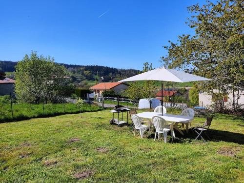 a table and chairs and an umbrella in the grass at Gîte du p'tit randonneur in Verrières-en-Forez