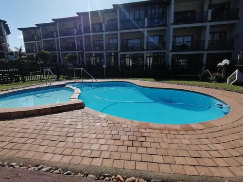 a swimming pool in front of a building at Topanga Holiday Apartment in Uvongo Beach