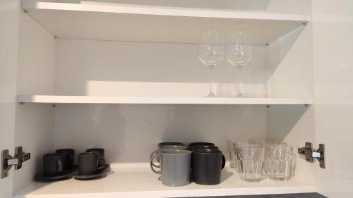 a shelf with wine glasses and other items on it at Helena Stúdió Apartman in Siófok