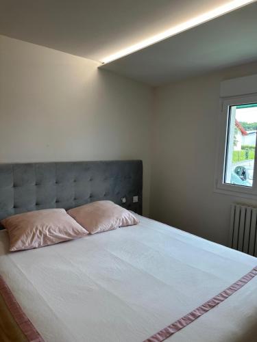 une chambre avec un grand lit avec des oreillers roses dans l'établissement maison avec piscine, à Guéthary