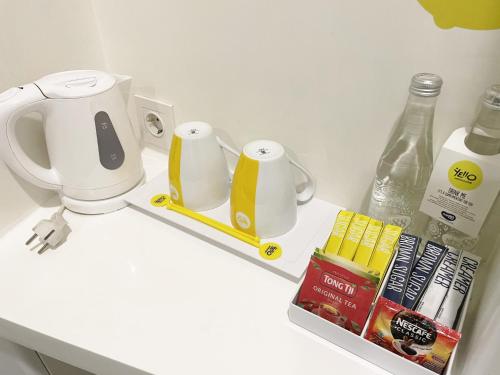 a white counter with cups and books on a shelf at YELLO Hotel Paskal Bandung in Bandung