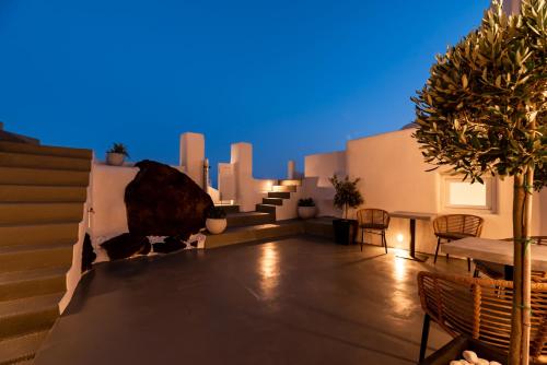 a rooftop patio with chairs and a table and trees at Twenty One Suites in Oia