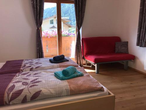 een slaapkamer met een bed, een stoel en een raam bij Ferienwohnung Marianne in Söll