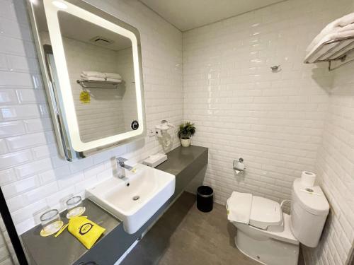 a white bathroom with a sink and a toilet at YELLO Hotel Paskal Bandung in Bandung