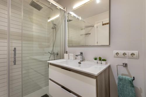a white bathroom with a sink and a shower at Flat just 280 m from the beach in Can Picafort