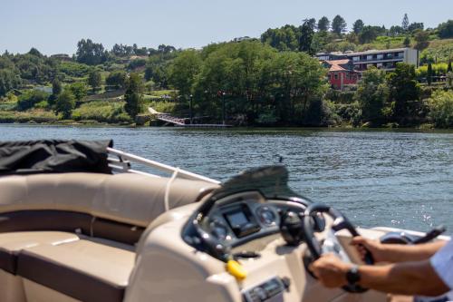 a person driving a boat on a body of water at Vinha Boutique Hotel - The Leading Hotels of the World in Vila Nova de Gaia