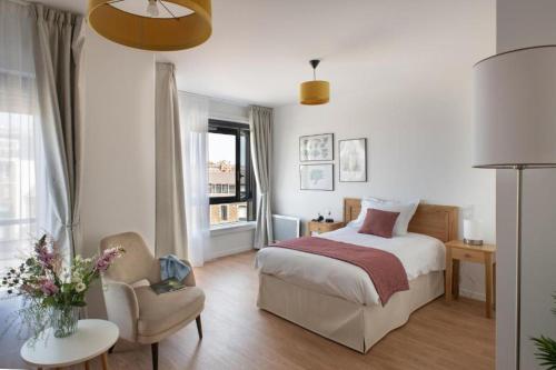 une chambre avec un lit, une chaise et une fenêtre dans l'établissement Résidence Services Seniors DOMITYS - LA BELLE EPOQUE, à Dinard