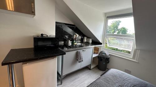 uma pequena cozinha com um balcão e uma janela em Economic Studio in the heart of Chiswick - London em Londres
