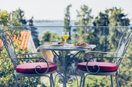 a table with a plate of food and a glass of wine at Pharia Hotel and Apartments - by the beach in Hvar