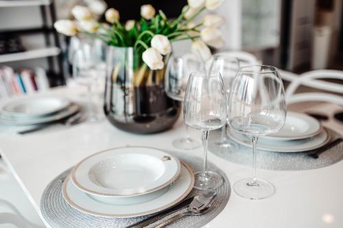 einen Tisch mit Gläsern und Tellern und eine Vase Blumen in der Unterkunft Apartament Staszica Nowa Sól in Nowa Sól