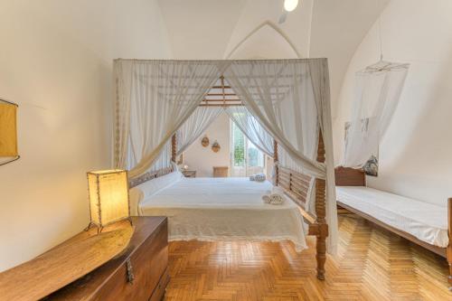 1 dormitorio con cama con dosel y ventana en Villa Blu La Patronale en Castro di Lecce