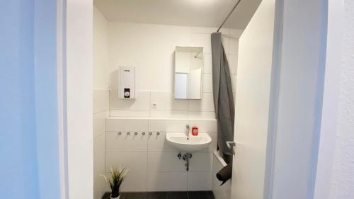 a white bathroom with a sink and a mirror at Cozy Apartment in Remscheid in Radevormwald